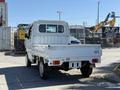 A white 2009 Suzuki Carry truck with a flatbed and a simple cabin design is parked, showing the rear view and a minimalistic exterior