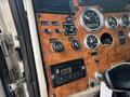 Dashboard of a 2008 Peterbilt 340 featuring various gauges switches and control knobs with a wood grain finish