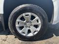 A close-up of a silver wheel with a five-spoke design and a black tire labeled All-Terrain T/A Sport. The Chevrolet logo is visible in the center of the wheel