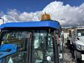 A 2010 New Holland T4050 tractor with a blue roof and a yellow warning light on top visible from the front with glass windows and controls inside the cabin