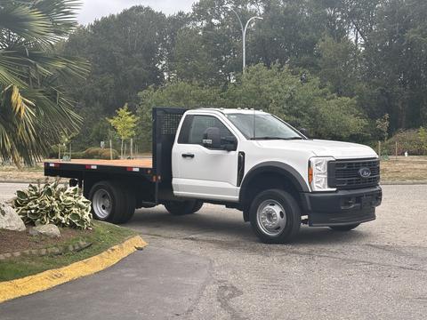 A 2023 Ford F-450 Super Duty with a flatbed design parked at an angle showcasing its front and side features
