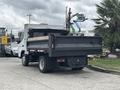 A 2015 Mitsubishi Fuso FE160 truck with a flatbed and rear dump feature is shown from the rear angle