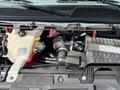 Engine compartment of a 2020 Chevrolet Express showing the radiator overflow tank and various engine components including hoses and the Vortec engine cover