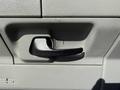 A black door handle on a light gray interior panel of a 2013 Ford Econoline