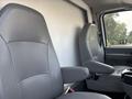 Two gray leather seats inside a 2008 Ford Econoline van with adjustable armrests and a simple design