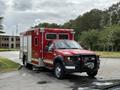 A red 2007 Ford F-550 ambulance with emergency markings and equipment visible on the exterior facing forward