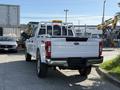 A 2021 Ford F-250 Super Duty in white with a pickup truck bed and a mounted light bar on the cab