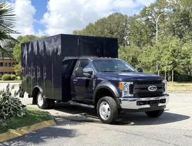 A 2017 Ford F-550 with a dark blue box-style cargo body parked at an angle showing the front and side of the truck