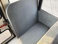 The image shows a gray vinyl seat inside a vehicle, featuring a smooth surface and simple design, positioned against a wall of another seat