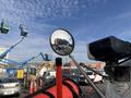 A 2013 Freightliner 114SD with a visible side mirror and reflection capturing nearby machinery and vehicles