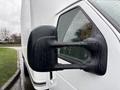 Close-up of the side mirror on a 2024 Ford E-450 showing a black housing design with a textured surface and droplets of rain on the glass