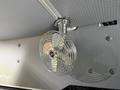 A chrome circular fan mounted on a ceiling with a textured surface visible around it