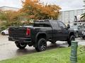 A 2022 GMC Sierra 3500HD pickup truck in black with large tires and a rugged design parked on grass angled slightly to showcase its rear and side features