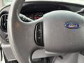 Close-up of the steering wheel in a 2006 Ford Econoline featuring controls for various functions and the Ford logo in the center