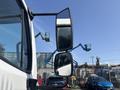A 2014 Freightliner M2 106 with a side mirror reflecting the view of machinery and equipment in the background