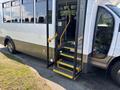 A 2020 Chevrolet Express bus with an open door and visible steps leading inside