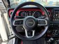 Steering wheel of a 2021 Jeep Wrangler featuring controls for audio and cruise settings with a prominent Jeep logo in the center