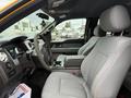 Interior of a 2014 Ford F-150 featuring grey cloth seats a steering wheel and dashboard with various controls and a console in the center