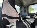 A black upholstered driver's seat and an adjacent gray passenger seat inside a 2015 Peterbilt 337 truck cabin
