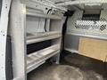 A 2017 Ford Transit Connect van interior featuring metal shelving units on one side and a wooden panel on the opposite side