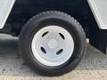 A close-up of a white wheel with a textured black tire showcasing six lug nut holes and a smooth rim surface