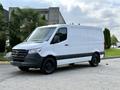 A white 2021 Mercedes-Benz Sprinter van with a black grille parked on a concrete surface