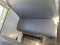 A gray vinyl bus seat in a school bus featuring a flat surface with no visible wear and a metal base