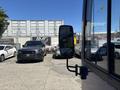 A 2018 Grande West Vicinity bus is parked with its side mirror visible in the foreground while various vehicles are positioned behind it