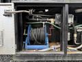 A blue hose reel with black hose coiled on it is stored in a compartment of a 2018 Kenworth T800 truck