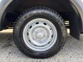 A close-up of a silver wheel of a 2018 Ford Transit-350 featuring a robust black tire with prominent tread patterns and a central hubcap