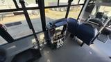 The interior of a 2021 Ford Transit featuring a compact seating area with two blue seats and a folding chair mounted on a frame with controls visible