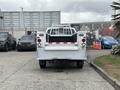 A 2013 Ford F-250 SD with a flatbed and rear lights facing the viewer parked on a paved surface