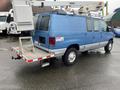 A blue 2006 Ford Econoline van with a ladder rack and equipment platform attached to the rear