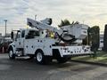 A 2013 International Durastar 4300 truck with an Altec aerial lift system mounted on the rear and a white utility body equipped with various compartments and lighting