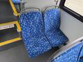 Two blue bus seats with a geometric pattern located in the foreground of a transit vehicle