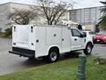 A white 2017 Ford F-350 SD utility truck with a service body and dual rear wheels parked on a grassy area