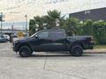 A black 2021 RAM 1500 pickup truck parked on a concrete surface with large black rims and a double cab design
