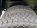 Close-up of a large, heavily treaded tire from a 2013 Freightliner 114SD showcasing its rugged texture and wear details
