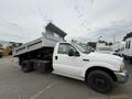 White 2004 Ford F-350 SD dump truck with an elevated bed and a black toolbox attached to the side