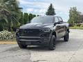 A black 2021 RAM 1500 pickup truck with a bold front grille and sporty design parked in a driveway