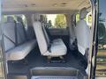The interior of a 2016 Ford Transit 150 featuring gray upholstered bench seats with seatbelts arranged in rows