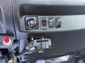 Close-up of the dashboard controls in a 2015 Hino 358 featuring a knob for adjustments and three switches alongside a mounted device connector