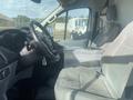Interior of a 2017 Ford Transit showing the driver's seat steering wheel and center console with gray fabric upholstery