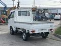 A white 2010 Daihatsu Hijet small truck with a flatbed and dual rear wheels visible from the rear angle