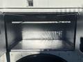 An empty storage compartment of a 2008 International 4400 with metallic walls and a single overhead shelf