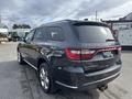 A 2015 Dodge Durango in dark gray positioned at an angle showing its rear and side profile with a shiny finish and distinctive tail lights
