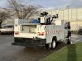 A 2010 Ford F-550 with a utility body featuring equipment storage compartments and a mounted aerial work platform at the rear