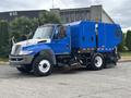 A blue and white 2013 International DuraStar 4300 street sweeper with a large blue compartment and a front-mounted broom
