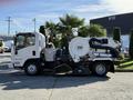 A white 2016 Isuzu NPR street sweeper truck with a large vacuum tank and broom attachment on the front