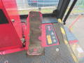 A worn footrest in a Toro Grounds Master 5910 with distinct red and black coloring and warning labels on the floorplate